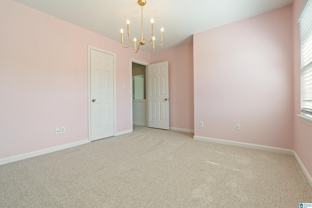 empty room featuring an inviting chandelier, baseboards, and light carpet