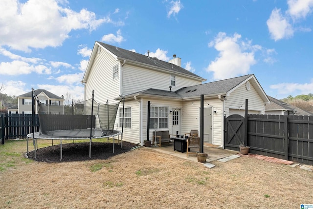 back of property featuring a gate, a patio, a trampoline, a fenced backyard, and a yard