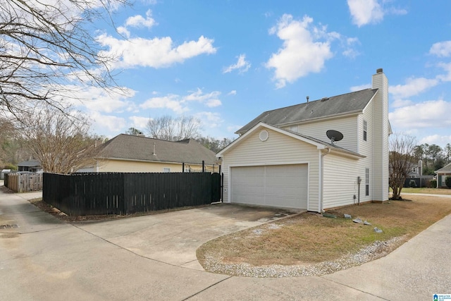 view of side of home with concrete driveway, an attached garage, fence, and a chimney