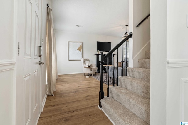 entryway with stairs, wood finished floors, and baseboards