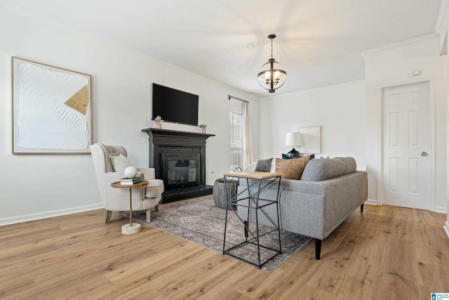 living area with a glass covered fireplace, crown molding, light wood-type flooring, and baseboards