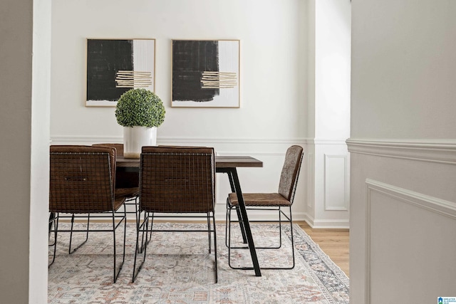 dining room with a decorative wall, wood finished floors, and a wainscoted wall