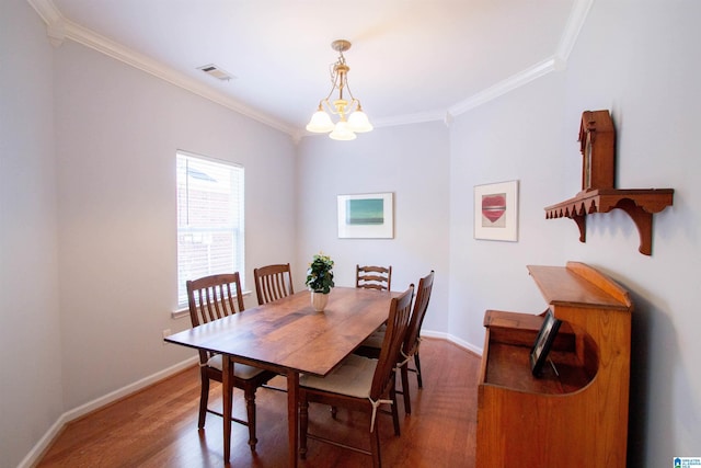 dining area featuring baseboards, wood finished floors, visible vents, and ornamental molding