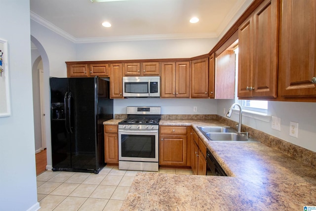 kitchen with brown cabinets, black appliances, a sink, arched walkways, and light tile patterned flooring