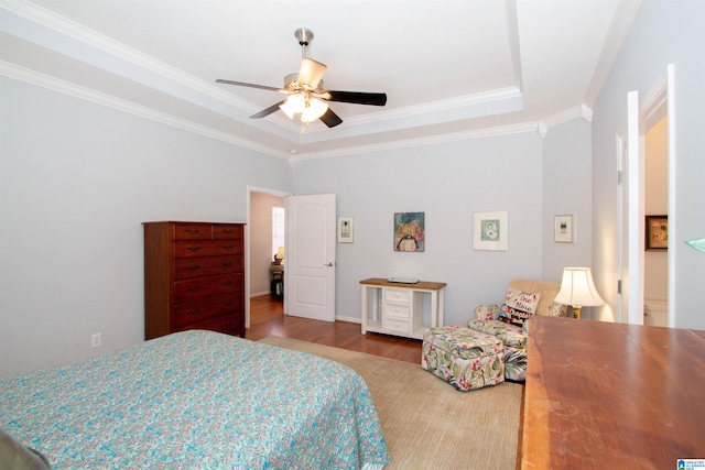 bedroom featuring crown molding, wood finished floors, a tray ceiling, and ceiling fan