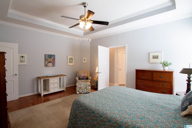 bedroom with a tray ceiling, wood finished floors, and crown molding