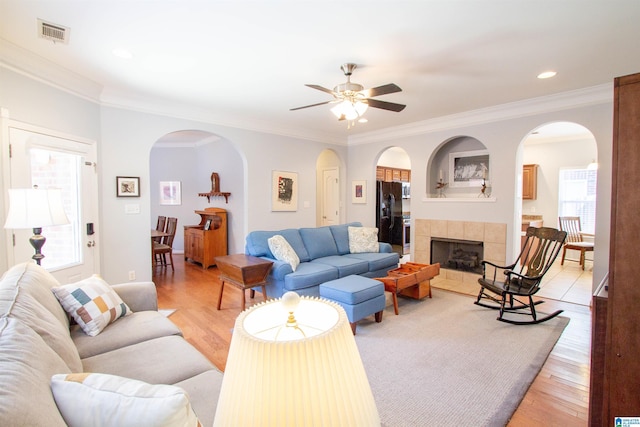 living area featuring light wood finished floors, visible vents, arched walkways, and a ceiling fan