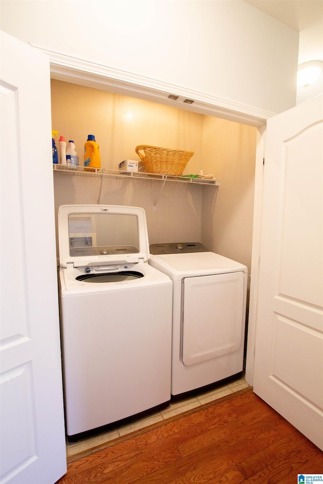 clothes washing area featuring laundry area, light wood-style floors, and washing machine and clothes dryer