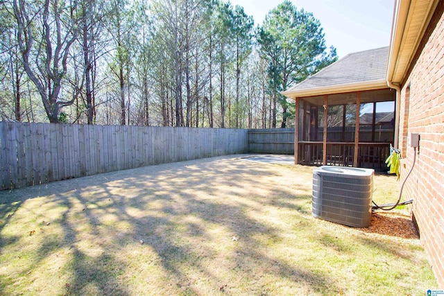 view of yard with a sunroom, a fenced backyard, and central AC