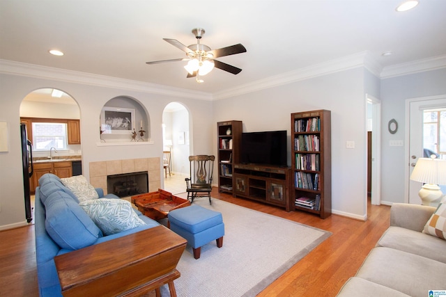 living room with a wealth of natural light, arched walkways, light wood finished floors, and ceiling fan