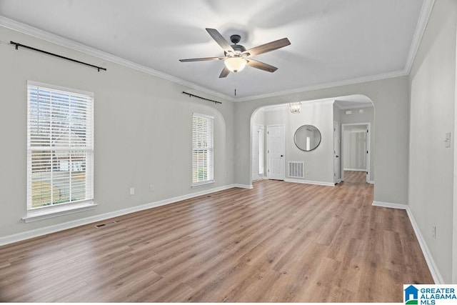 unfurnished living room featuring crown molding, a ceiling fan, visible vents, and arched walkways