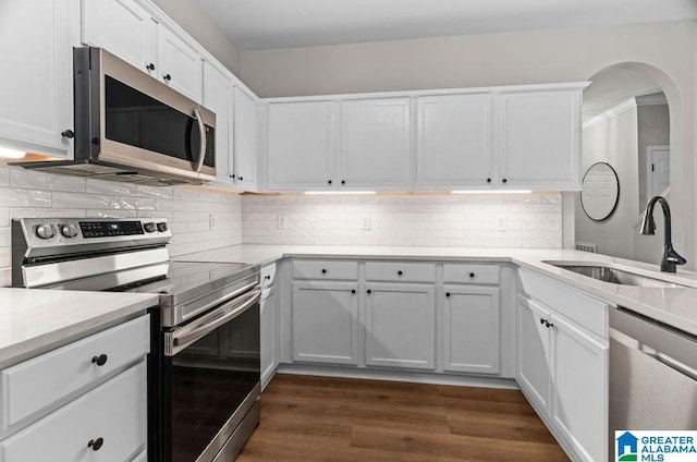 kitchen featuring backsplash, dark wood-type flooring, appliances with stainless steel finishes, white cabinetry, and a sink