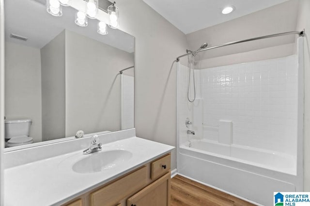 bathroom with vanity, wood finished floors, visible vents, shower / bath combination, and toilet