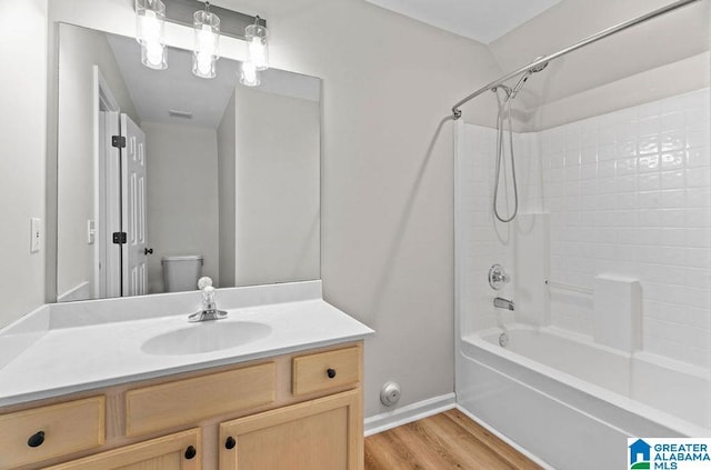 full bathroom with vanity, wood finished floors, baseboards, toilet, and shower / bathtub combination