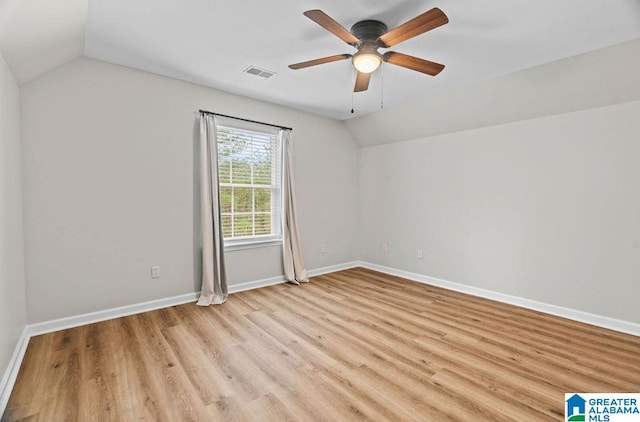 unfurnished room featuring baseboards, visible vents, lofted ceiling, light wood-style flooring, and ceiling fan