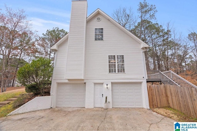 view of home's exterior with a chimney, concrete driveway, and an attached garage