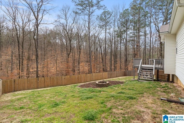 view of yard with a wooden deck, a fire pit, a fenced backyard, and stairway