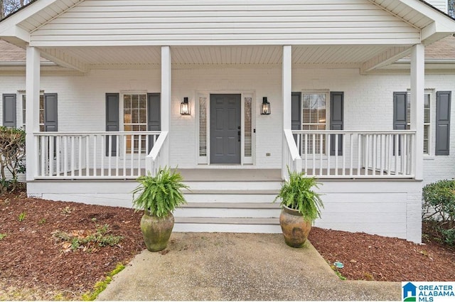 entrance to property with brick siding and a porch