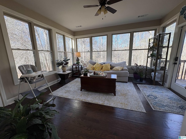 living room featuring visible vents, dark wood-type flooring, and a ceiling fan