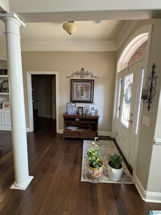 foyer entrance featuring dark wood-type flooring, decorative columns, baseboards, and ornamental molding