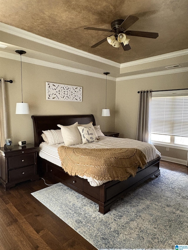 bedroom with a raised ceiling, crown molding, wood finished floors, and ceiling fan