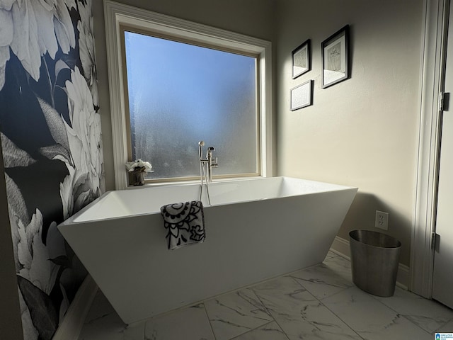 bathroom featuring a soaking tub, marble finish floor, and baseboards