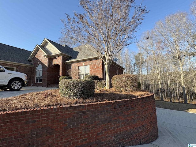 view of front facade featuring brick siding and roof with shingles