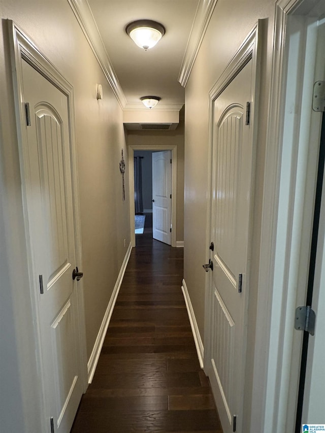 hall featuring dark wood-type flooring, baseboards, and ornamental molding