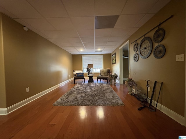 interior space featuring a drop ceiling, baseboards, and wood finished floors