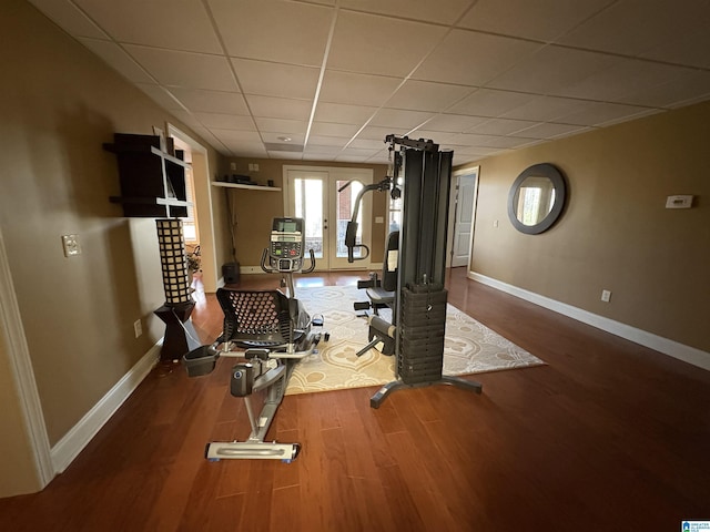 exercise area with baseboards, a paneled ceiling, and wood finished floors