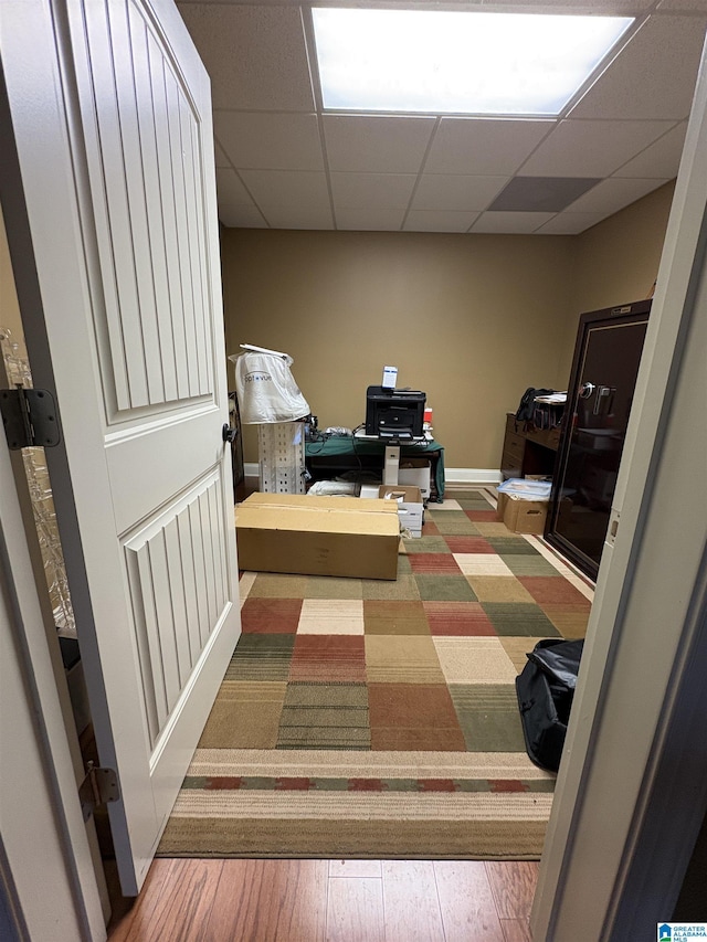 interior space with a drop ceiling, baseboards, and hardwood / wood-style flooring