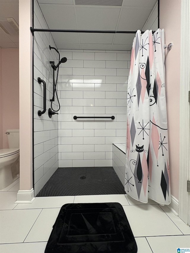 bathroom featuring tiled shower, toilet, and tile patterned flooring