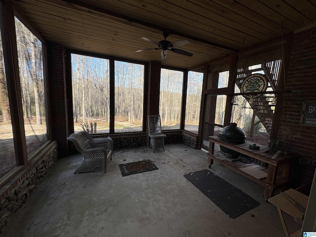 unfurnished sunroom featuring a wealth of natural light, wood ceiling, and a ceiling fan