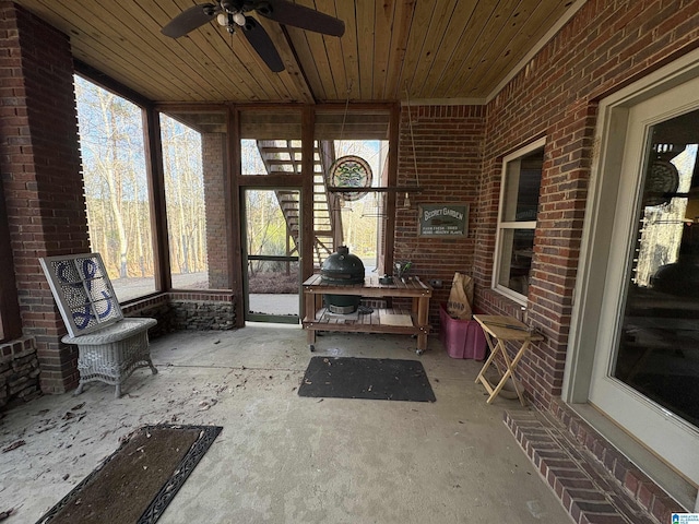 unfurnished sunroom with wood ceiling and ceiling fan