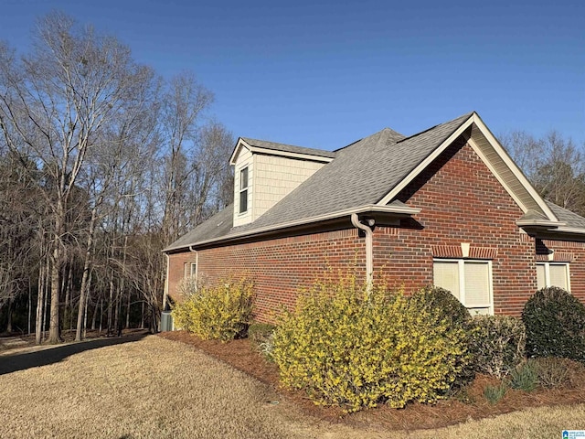 view of property exterior featuring brick siding and a shingled roof