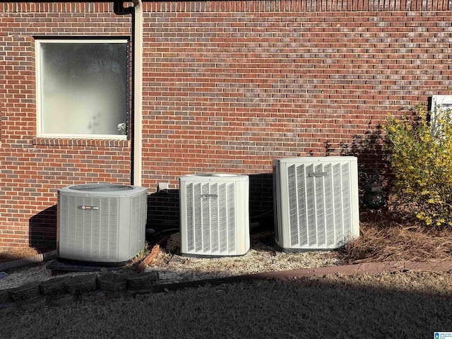 exterior details featuring cooling unit and brick siding