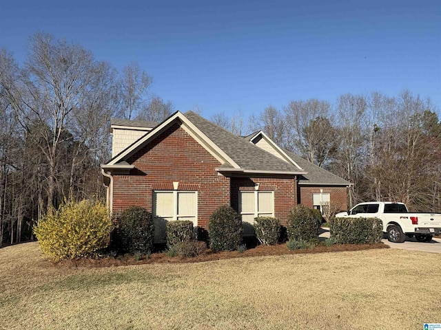 view of home's exterior with a lawn, brick siding, and a shingled roof