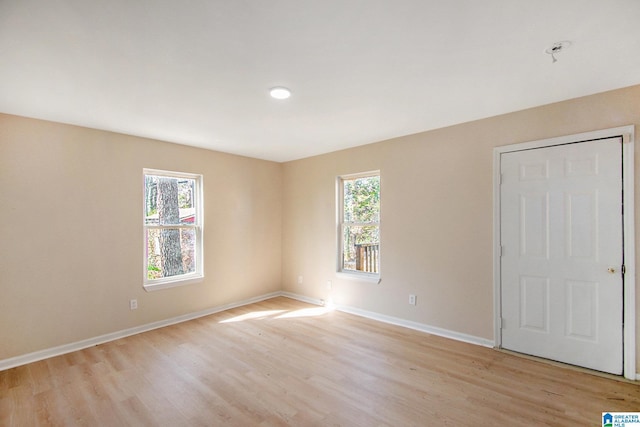 unfurnished room with a healthy amount of sunlight, light wood-type flooring, and baseboards