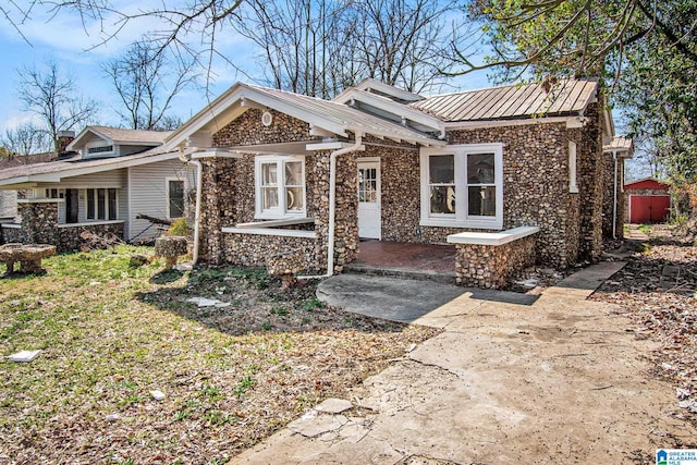 view of front of house featuring stone siding, metal roof, and a standing seam roof