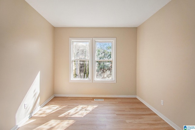 empty room featuring light wood finished floors, visible vents, and baseboards