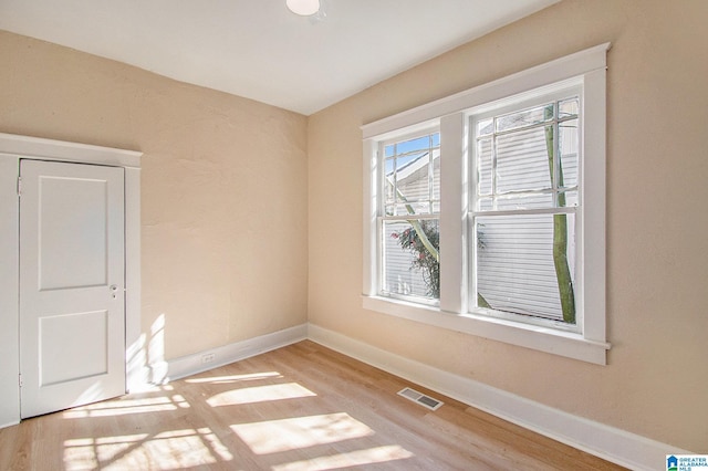 empty room featuring visible vents, baseboards, and light wood finished floors