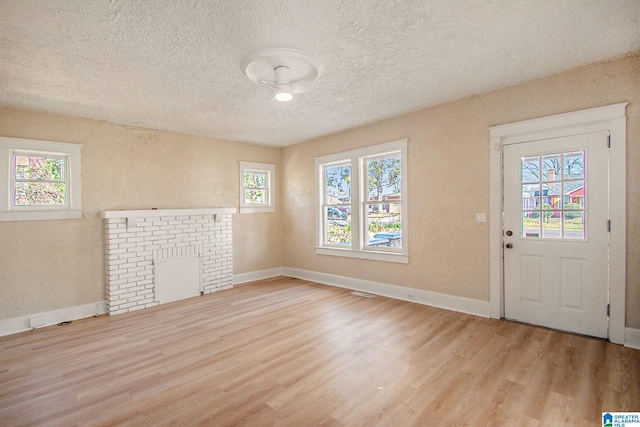 foyer entrance featuring a textured ceiling, wood finished floors, baseboards, and a healthy amount of sunlight