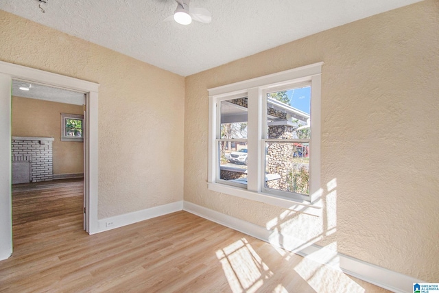 unfurnished room featuring wood finished floors, a textured wall, baseboards, and a textured ceiling