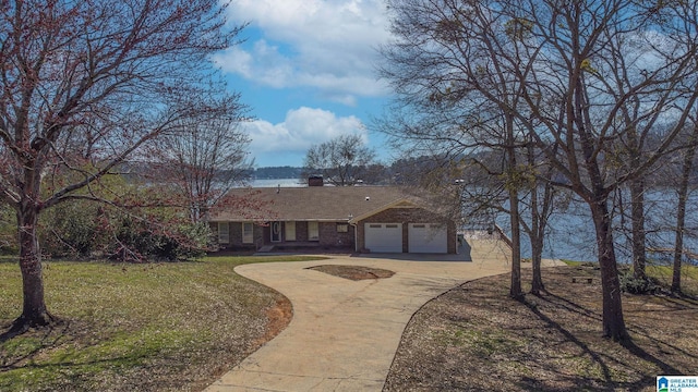 ranch-style home with a front yard, an attached garage, a chimney, concrete driveway, and brick siding