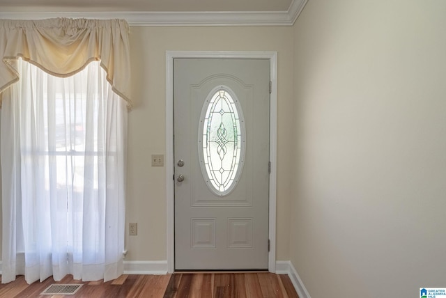 entryway featuring visible vents, baseboards, wood finished floors, and crown molding