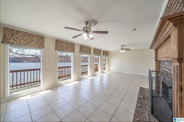 unfurnished living room with visible vents, a water view, light tile patterned flooring, and a ceiling fan