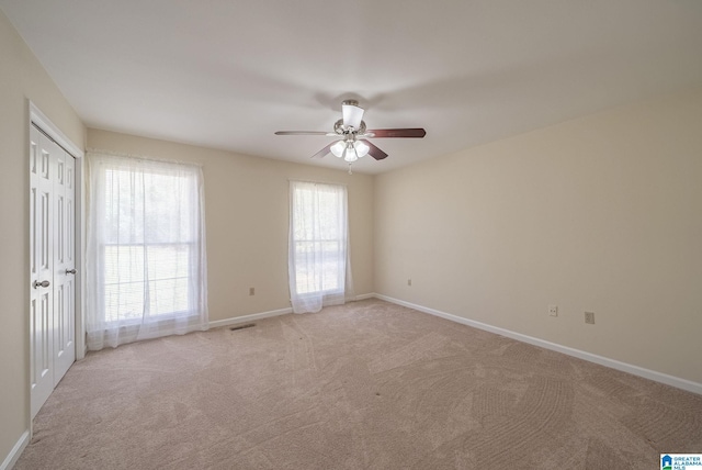 spare room featuring baseboards, light colored carpet, visible vents, and ceiling fan