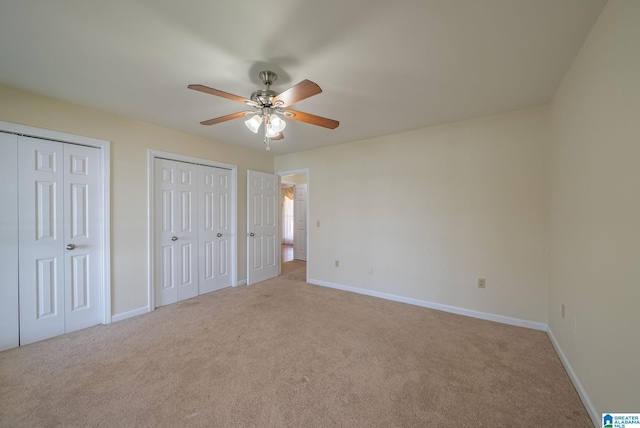 unfurnished bedroom featuring baseboards, carpet floors, a ceiling fan, and multiple closets