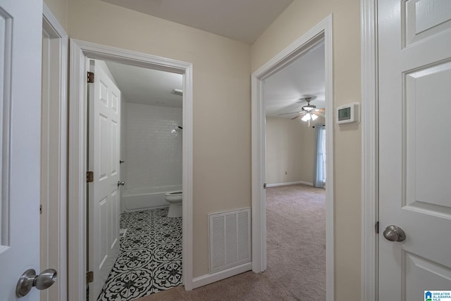 hallway with visible vents, baseboards, carpet flooring, and tile patterned flooring