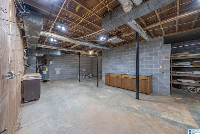 unfinished basement featuring a sink, electric water heater, and concrete block wall